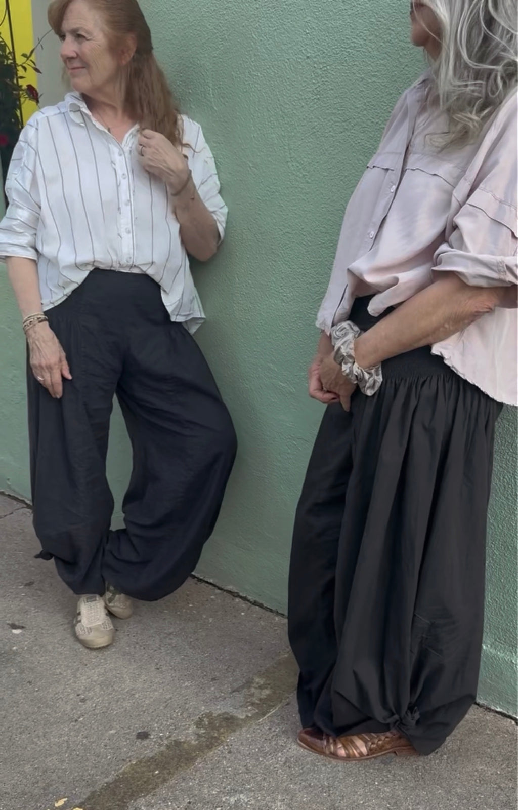 Two women wearing the Italian Pants front view and side view in Noir. relaxed fit