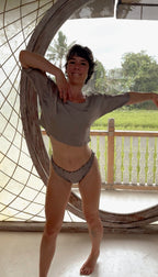 Woman dancing in The Ease Tee naturally dyed silk crop top in soft window light.